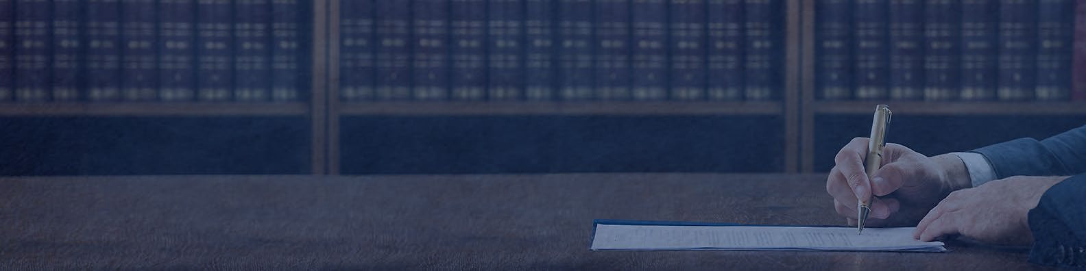 An attorney signing a document in front of a wall of law reports